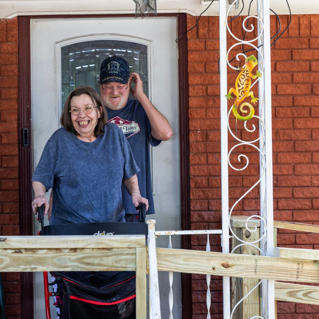 person with walker coming out of their front door smiling
