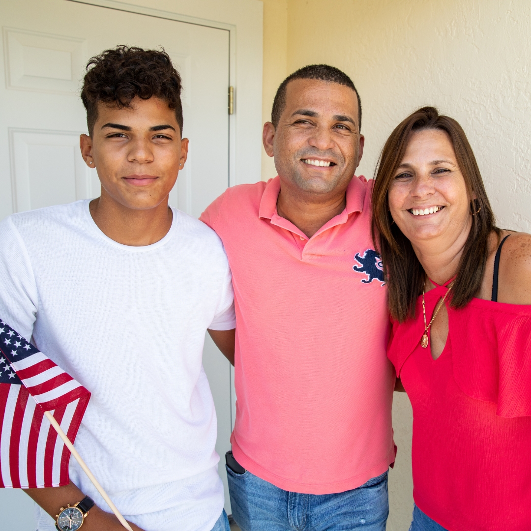 Three people standing in front of a door with an American flag